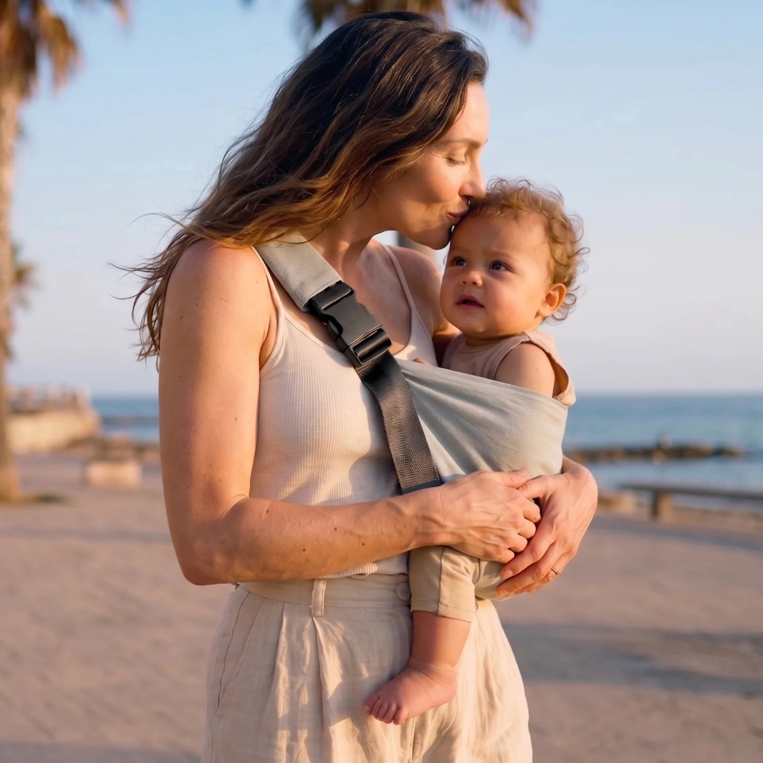 Portabebés ergonómico Bilby color gris Paris en uso — mamá y bebé disfrutando de la playa en primavera.