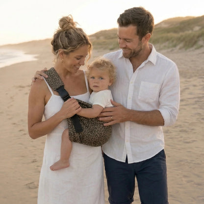 Familia elegante en la playa con bebé en portabebés Bilby Instinct leopardo
