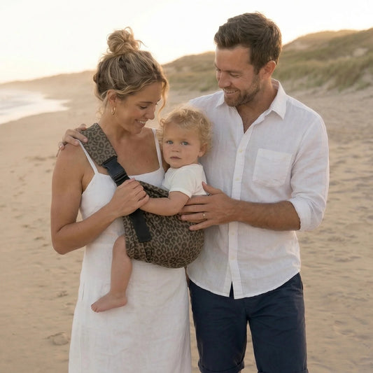 Familia elegante en la playa con bebé en portabebés Bilby Instinct leopardo
