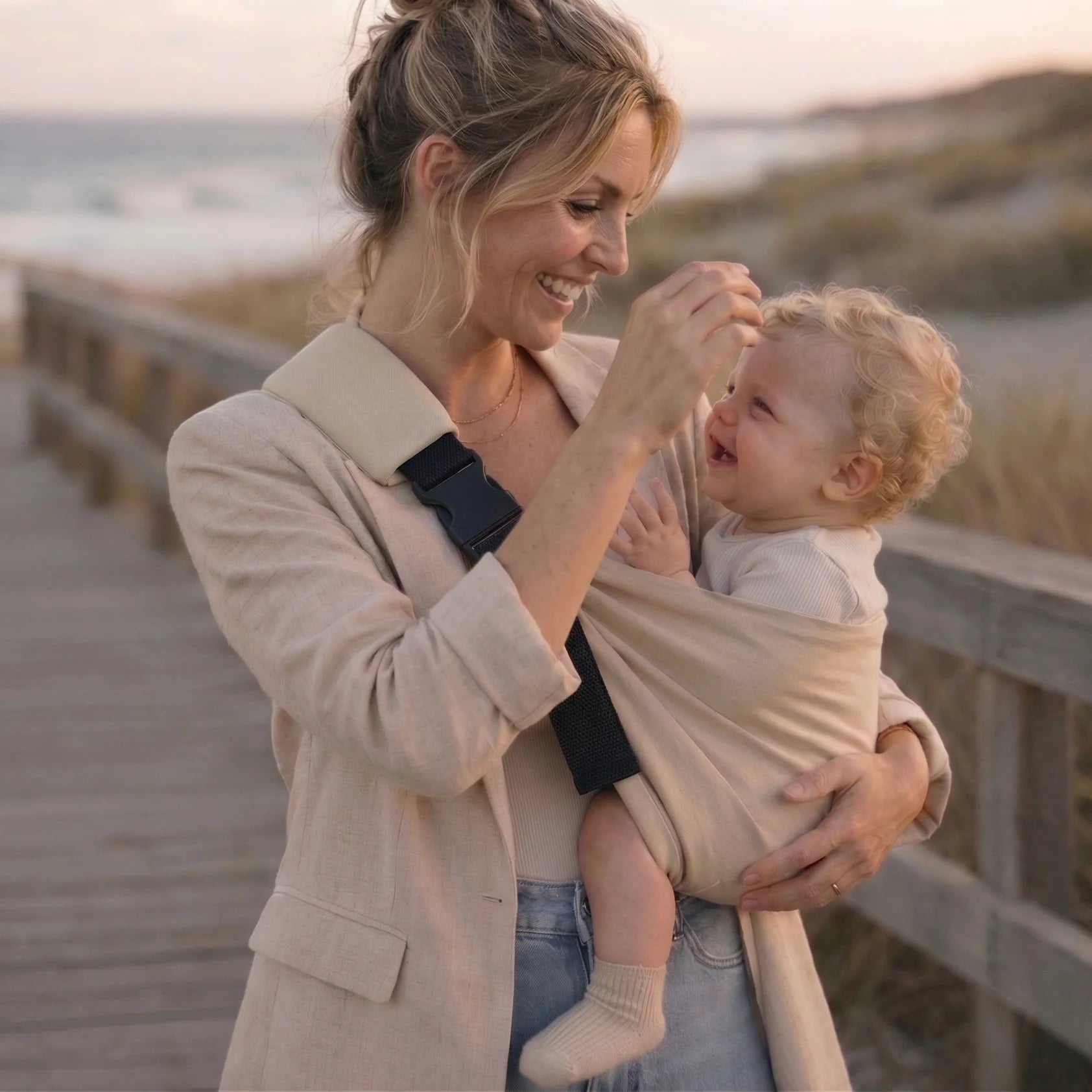 Madres en la playa con portabebés Bilby Taupe en tarde de verano