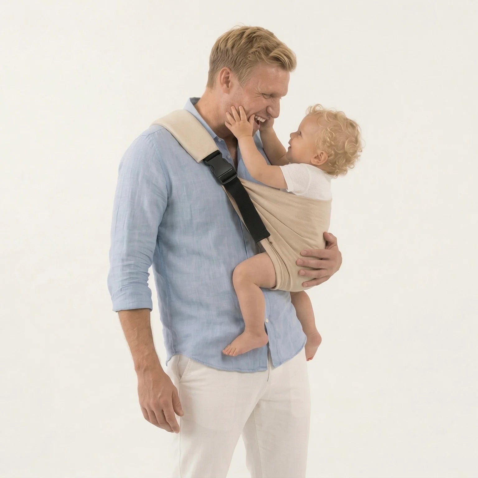 Padre con camisa azul y portabebés Bilby Taupe en sesión de estudio fondo blanco